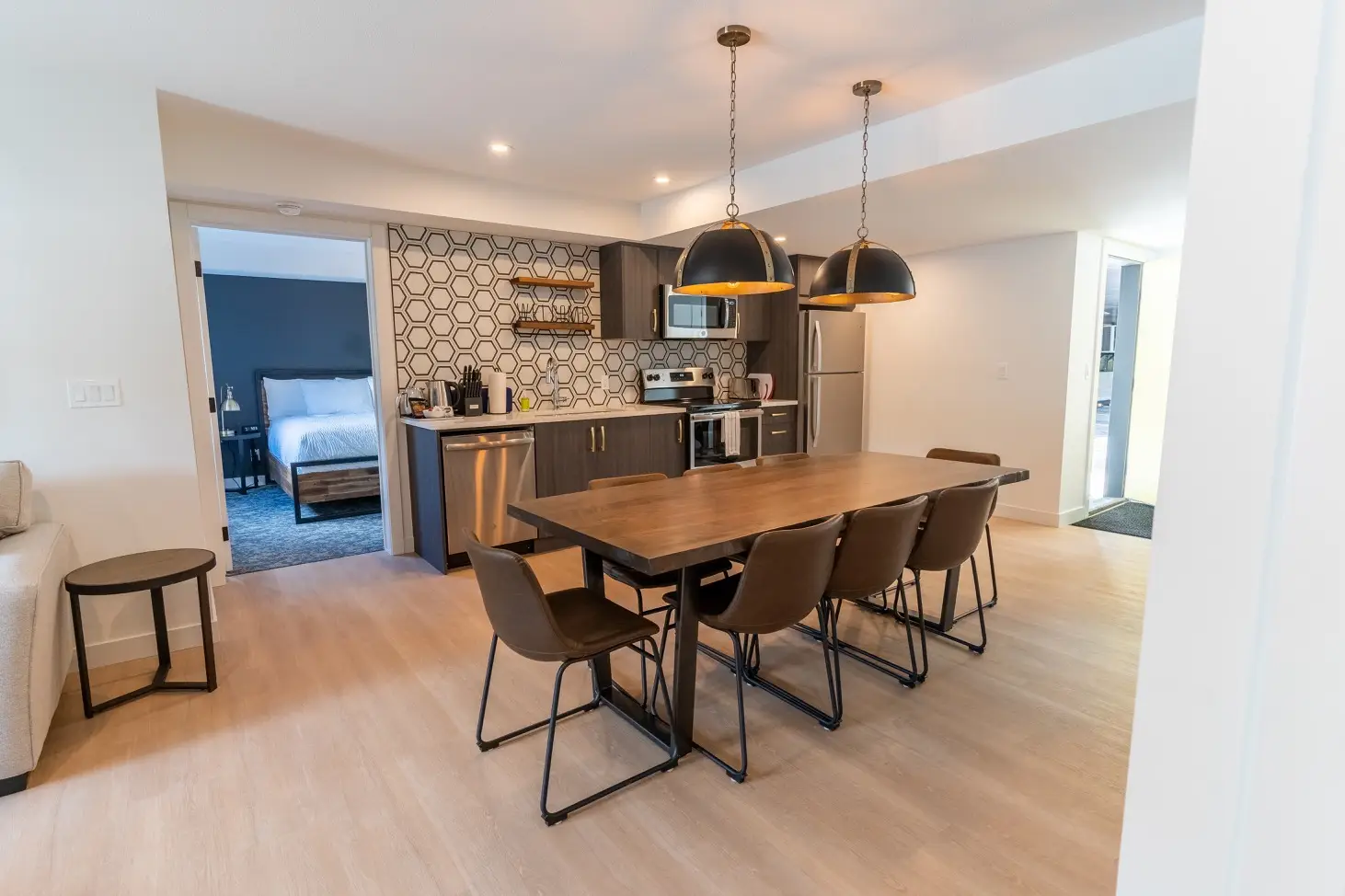 Modern open-plan kitchen and dining area in a Canmore suite with access to a bedroom.