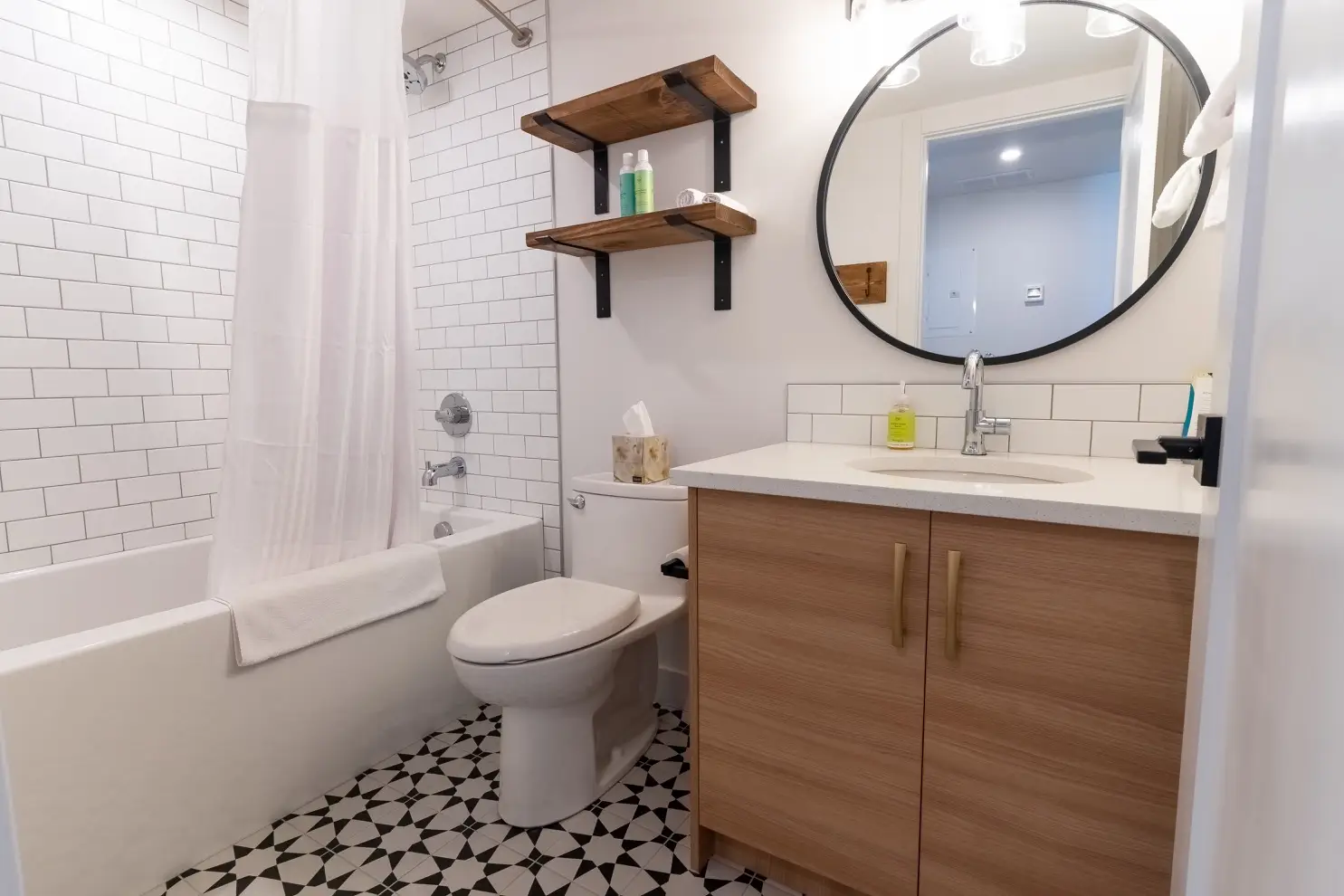 Modern bathroom with white subway tile, wood vanity, and black and white floor tiles.