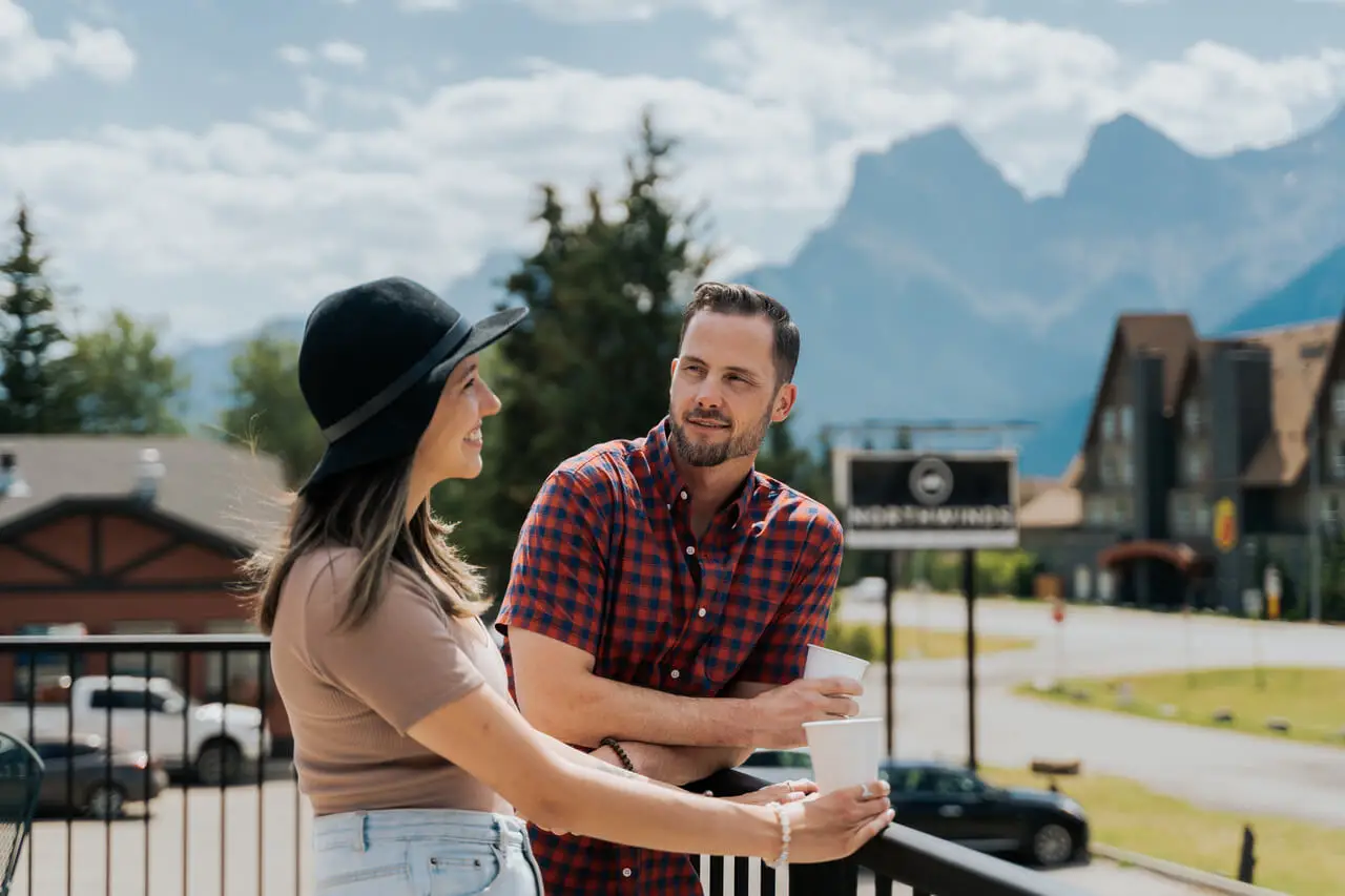 Couple enjoying drinks on a balcony at Canmore Northwinds with mountain views