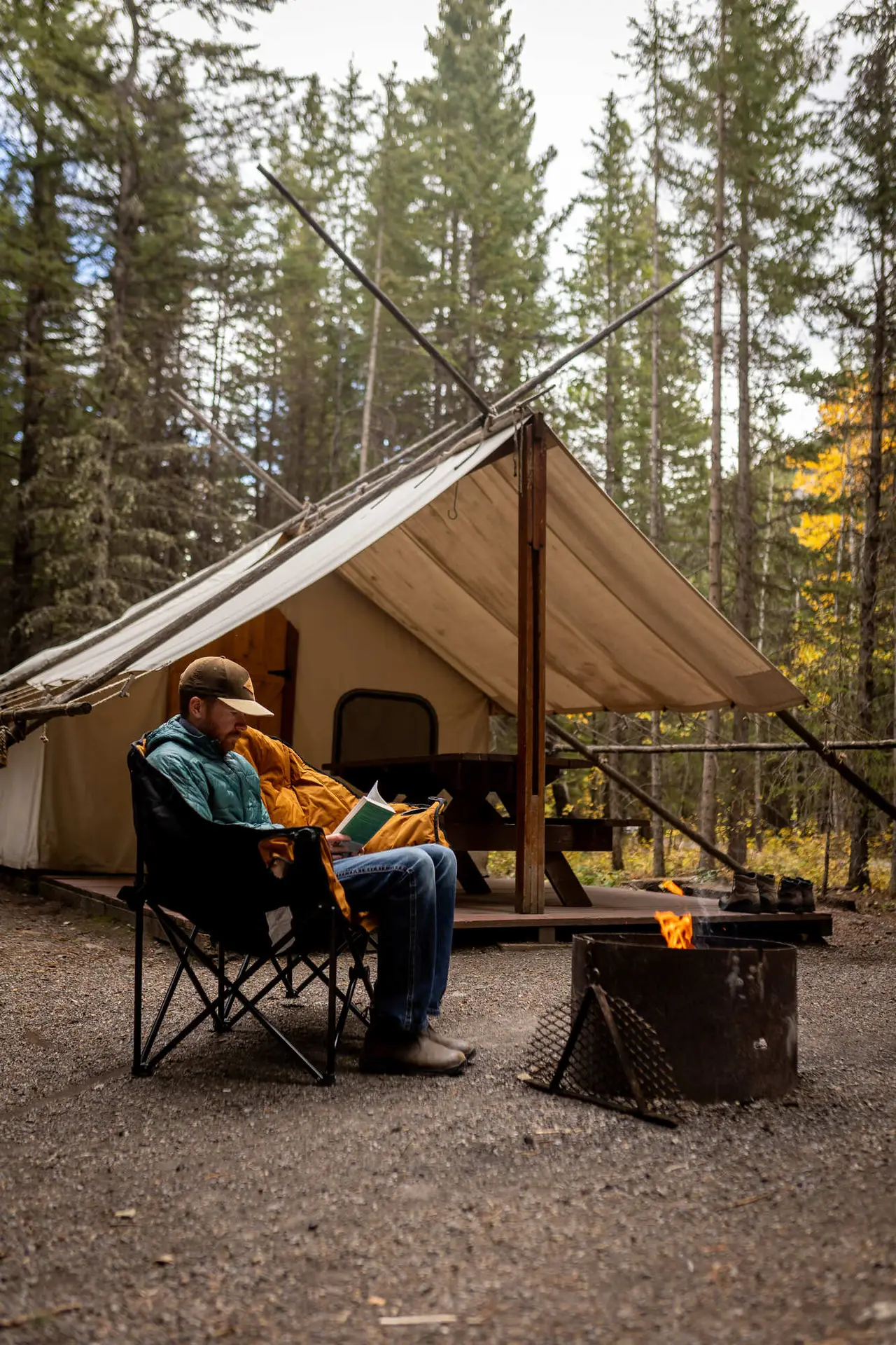 Man reading by campfire at Sundance by Basecamp glamping tent
