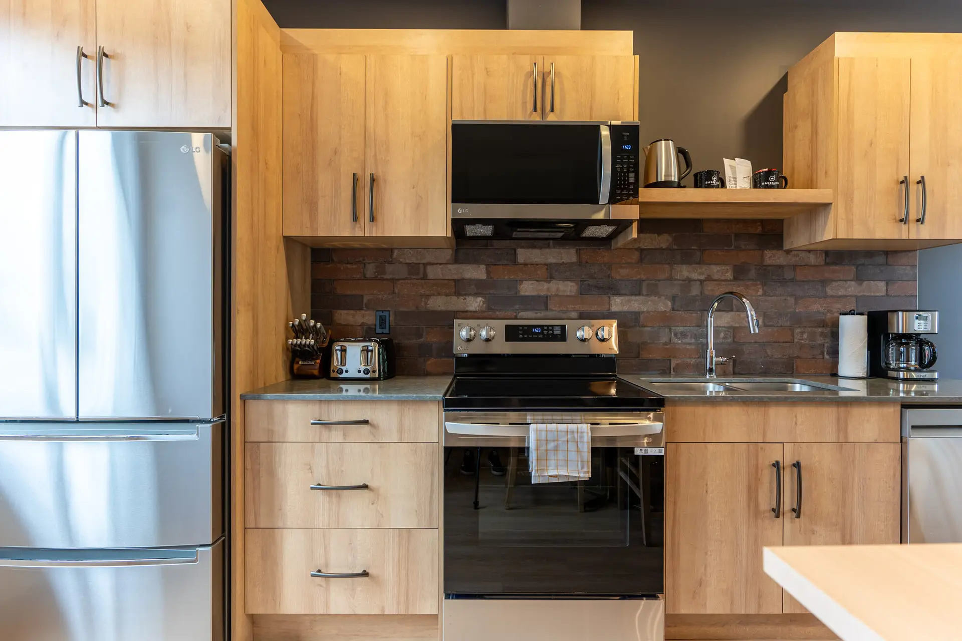 Modern kitchen in Basecamp Suites Revelstoke with stainless steel appliances and wood cabinetry.