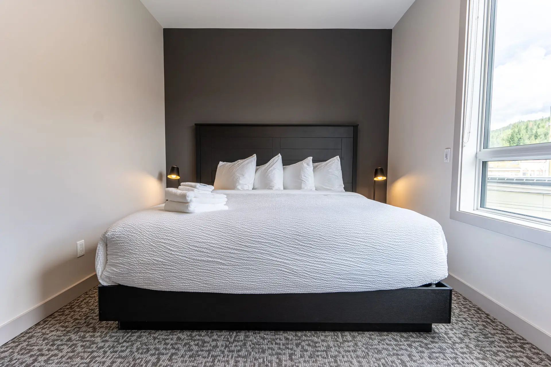 Basecamp Suites Revelstoke one bedroom suite features a king-size bed with white linens.