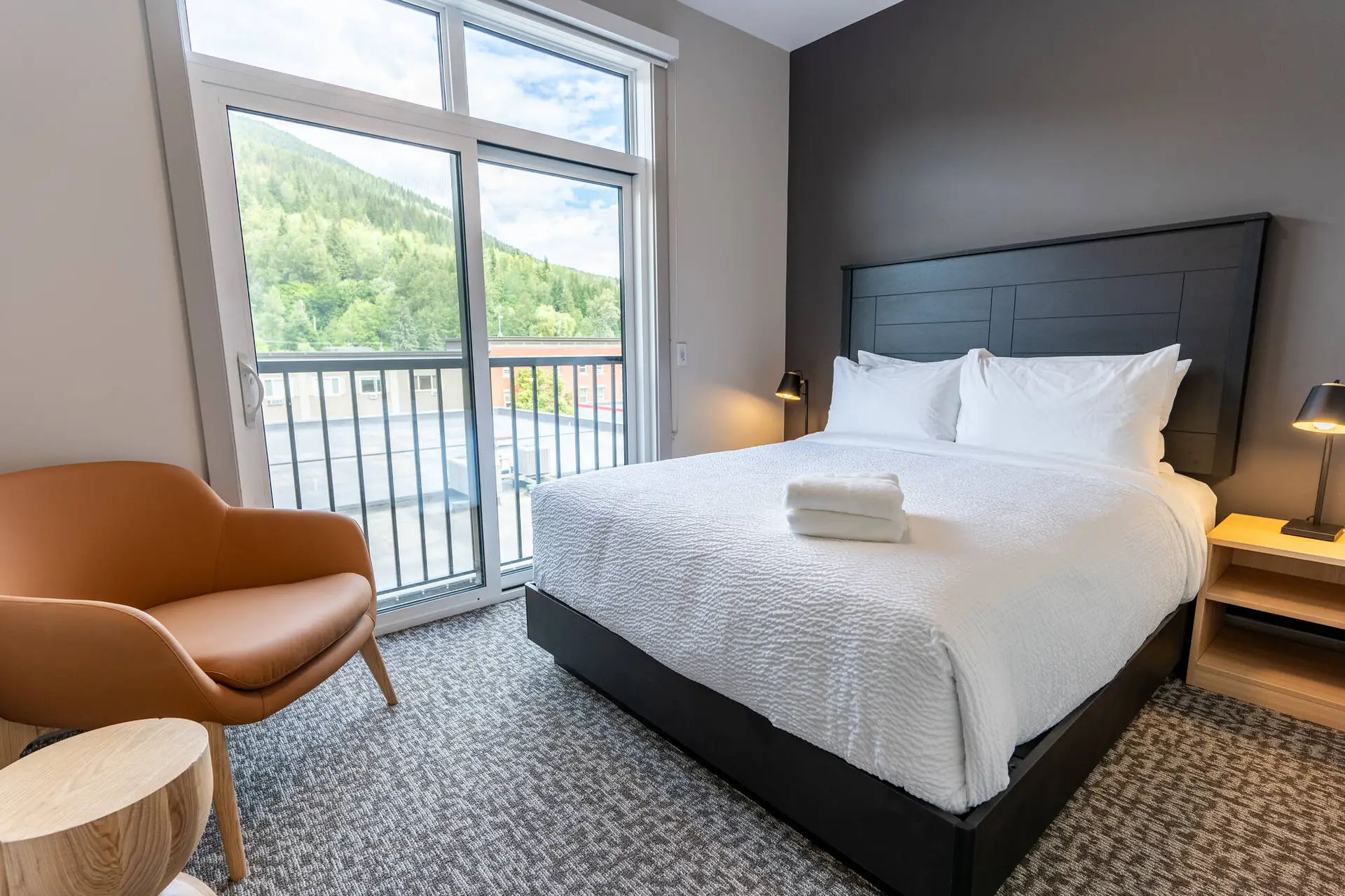 Basecamp Suites Revelstoke six bedroom suite with king bed, chair, and mountain view