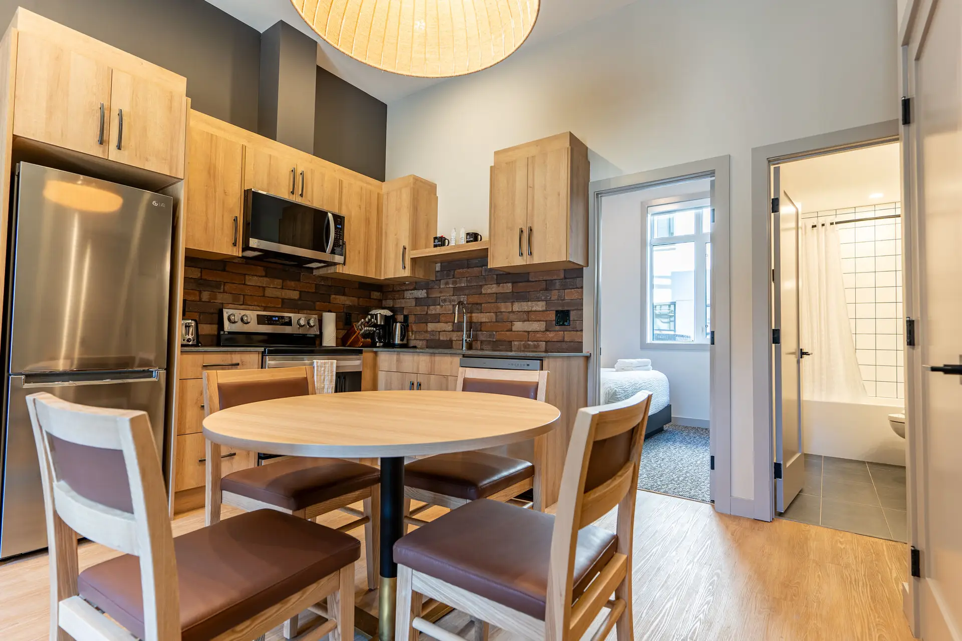 Basecamp Suites Revelstoke kitchen and dining area with a view of a bedroom.