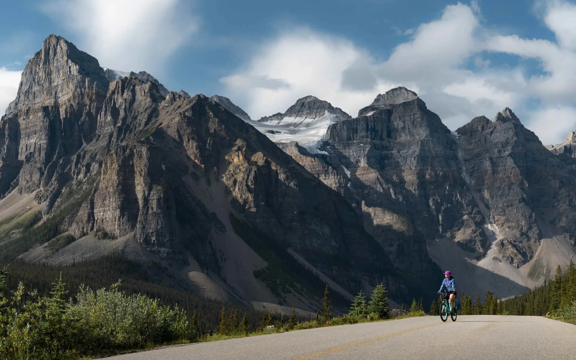 Cyclist on scenic Alberta highway with Rocky Mountains backdrop