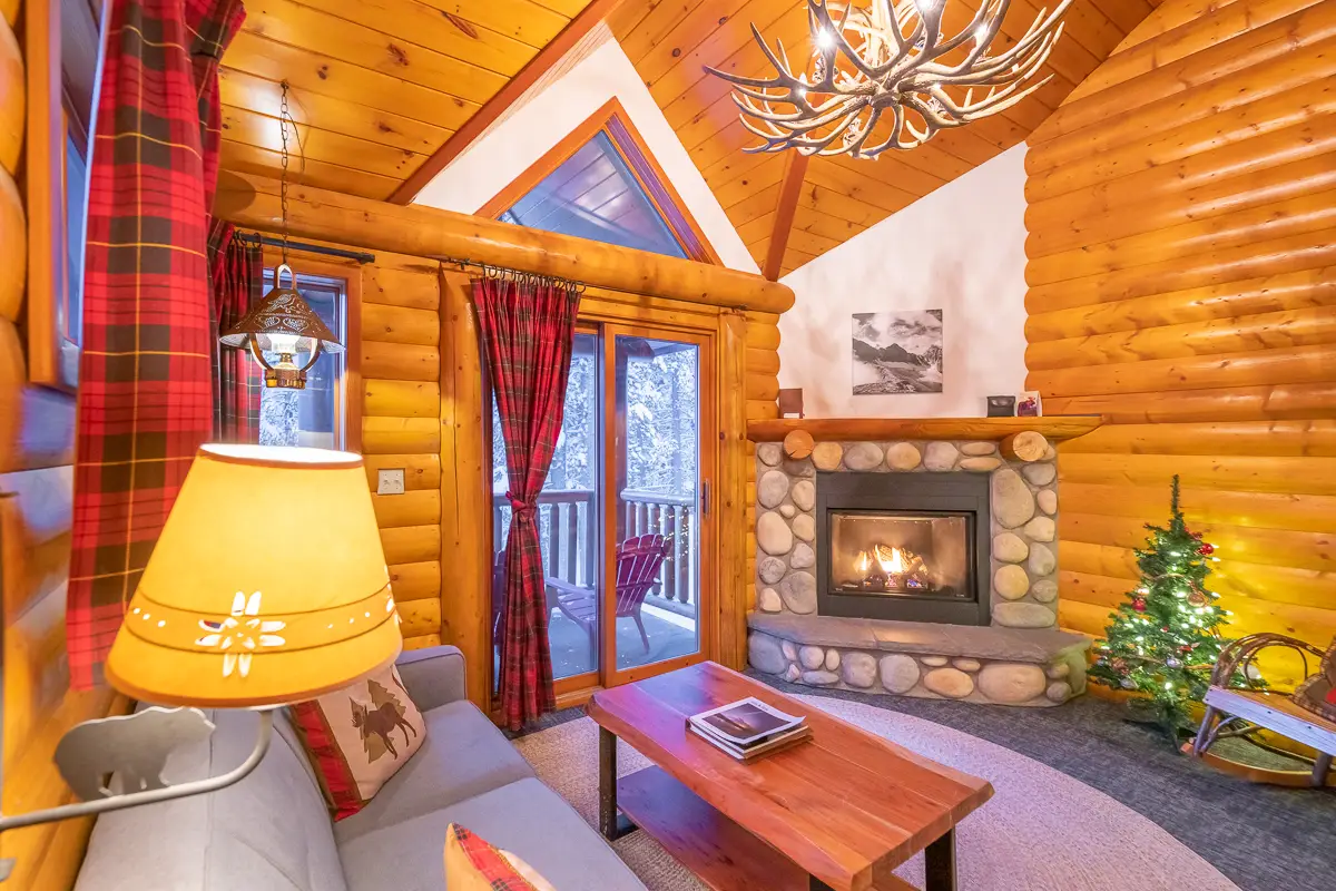 Cozy living room in Basecamp Baker Creek Superior Jacuzzi Suite with fireplace and Christmas tree.