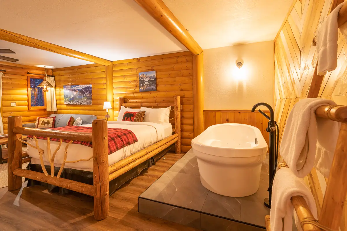 Jacuzzi Suite at Basecamp Baker Creek: Log bed, large tub, cozy mountain cabin decor.