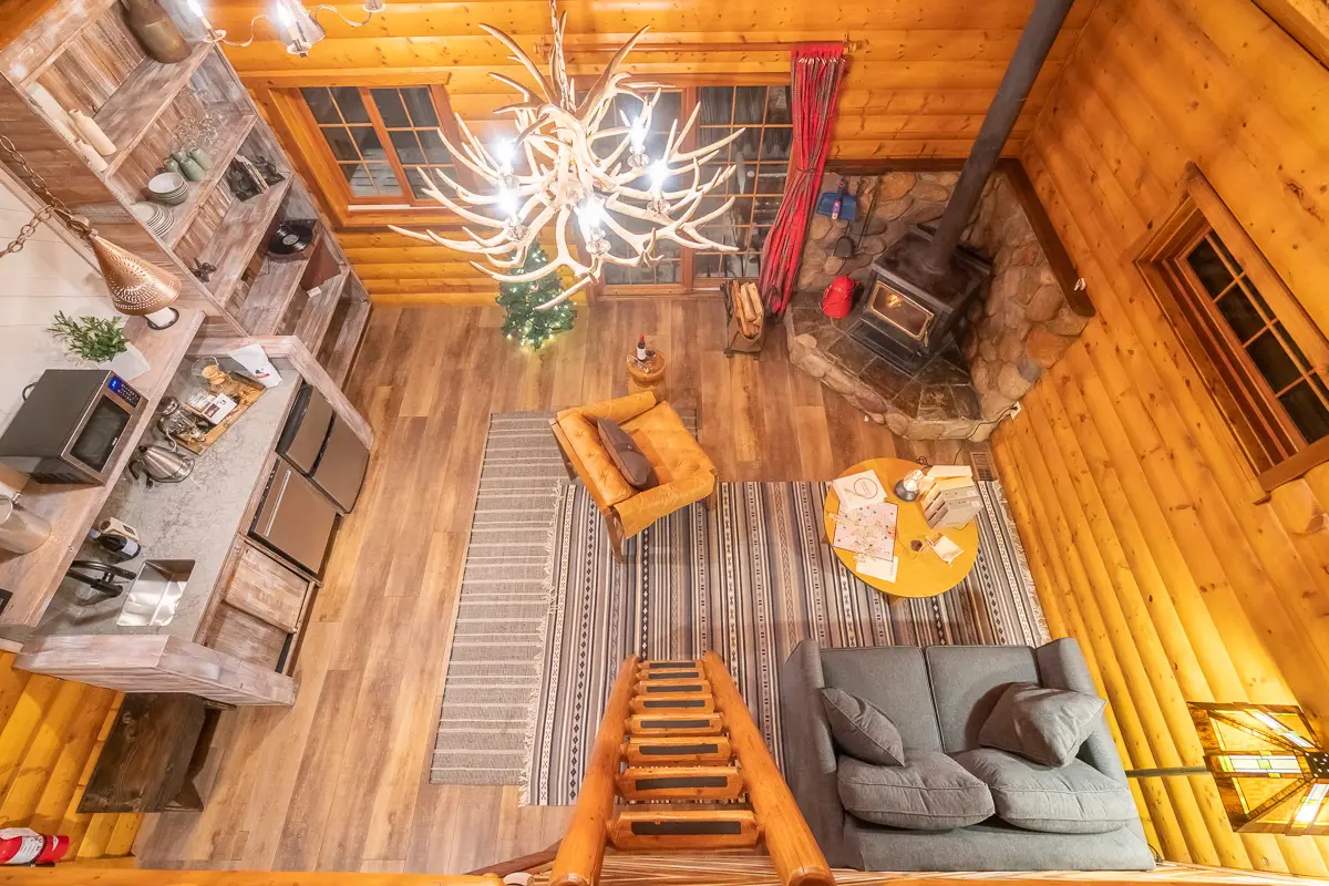 Basecamp Baker Creek cabin interior with loft, fireplace, and antler chandelier.