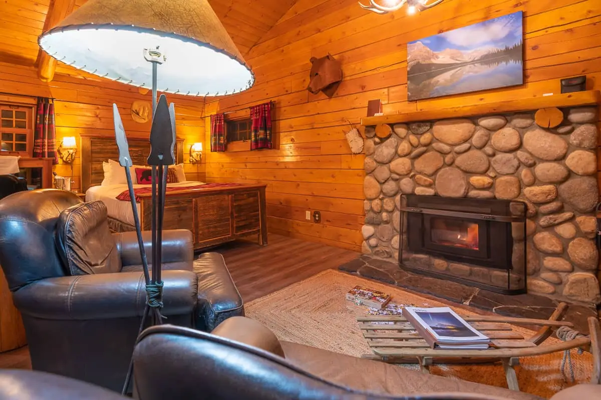 Cozy log cabin interior with stone fireplace, queen bed, and leather chairs