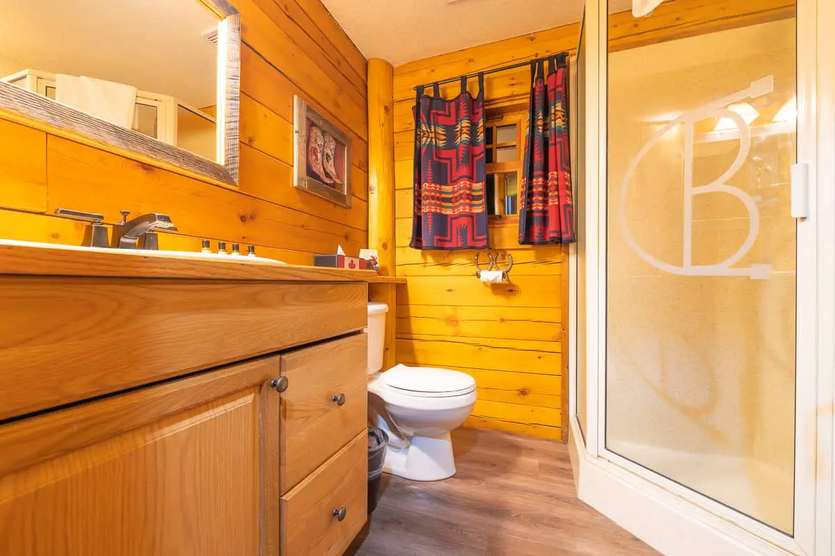 Basecamp Baker Creek Queen Cabin bathroom with wood paneling, vanity, and shower.