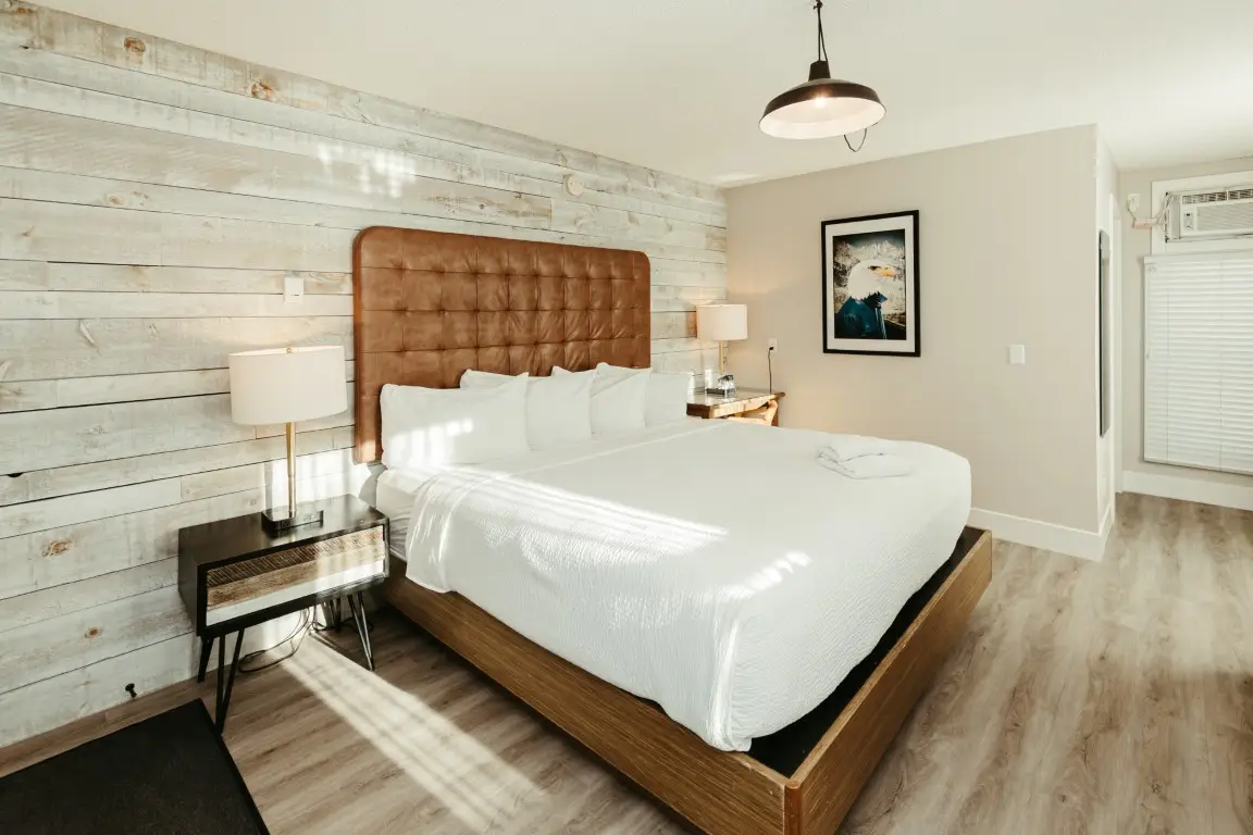 King bed in Basecamp Lamphouse Canmore dog-friendly room with rustic wood wall