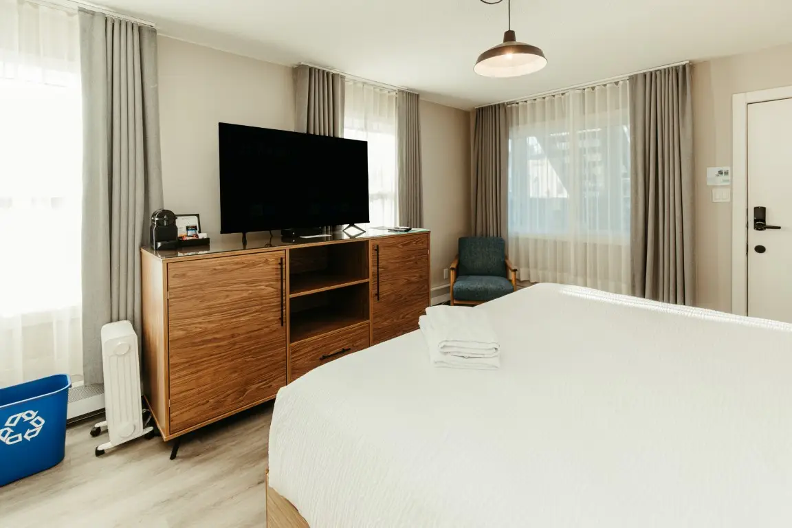 King bed in a dog-friendly Canmore hotel room with TV and amenities.