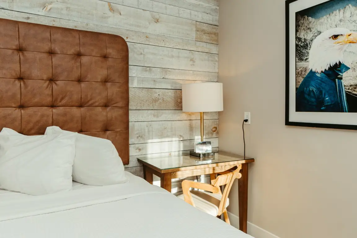 Canmore King Room: Tufted headboard, bedside table with lamp, and eagle art.