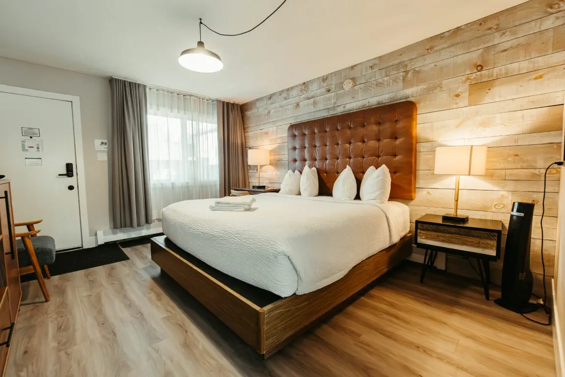 King bed in dog-friendly Basecamp Lamphouse Canmore room with wood accent wall.