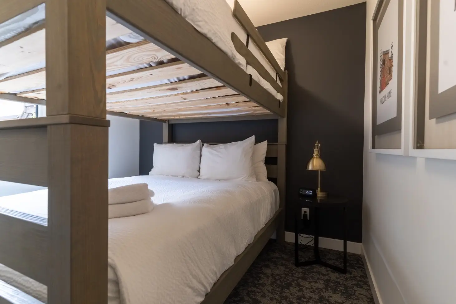 Bunk beds in a hotel room at Basecamp Suites Canmore, with a white comforter and pillows.