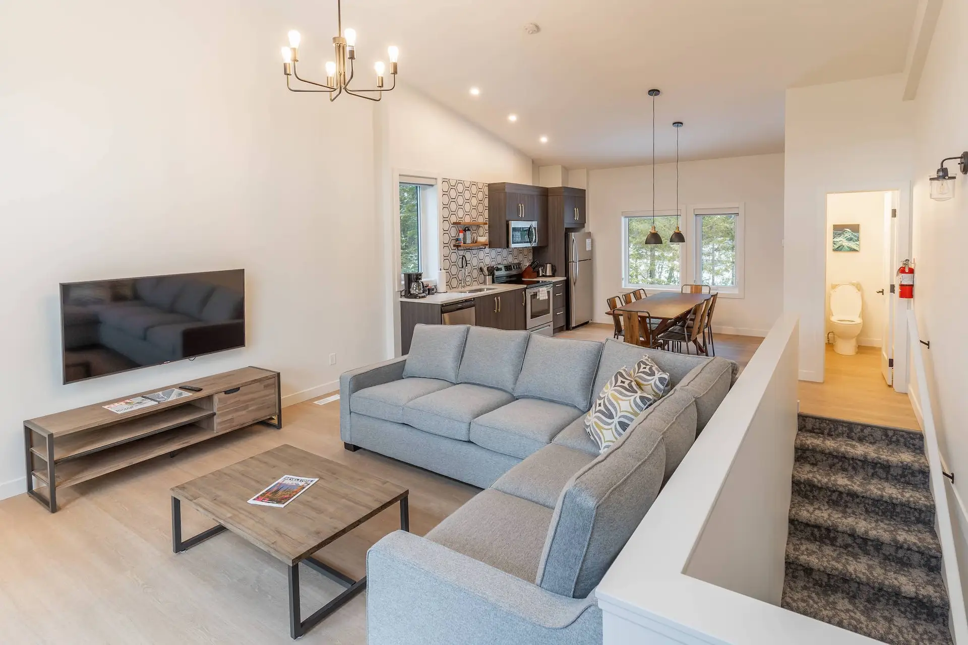 Revelstoke three-bedroom suite living area with sectional sofa, TV, and kitchen