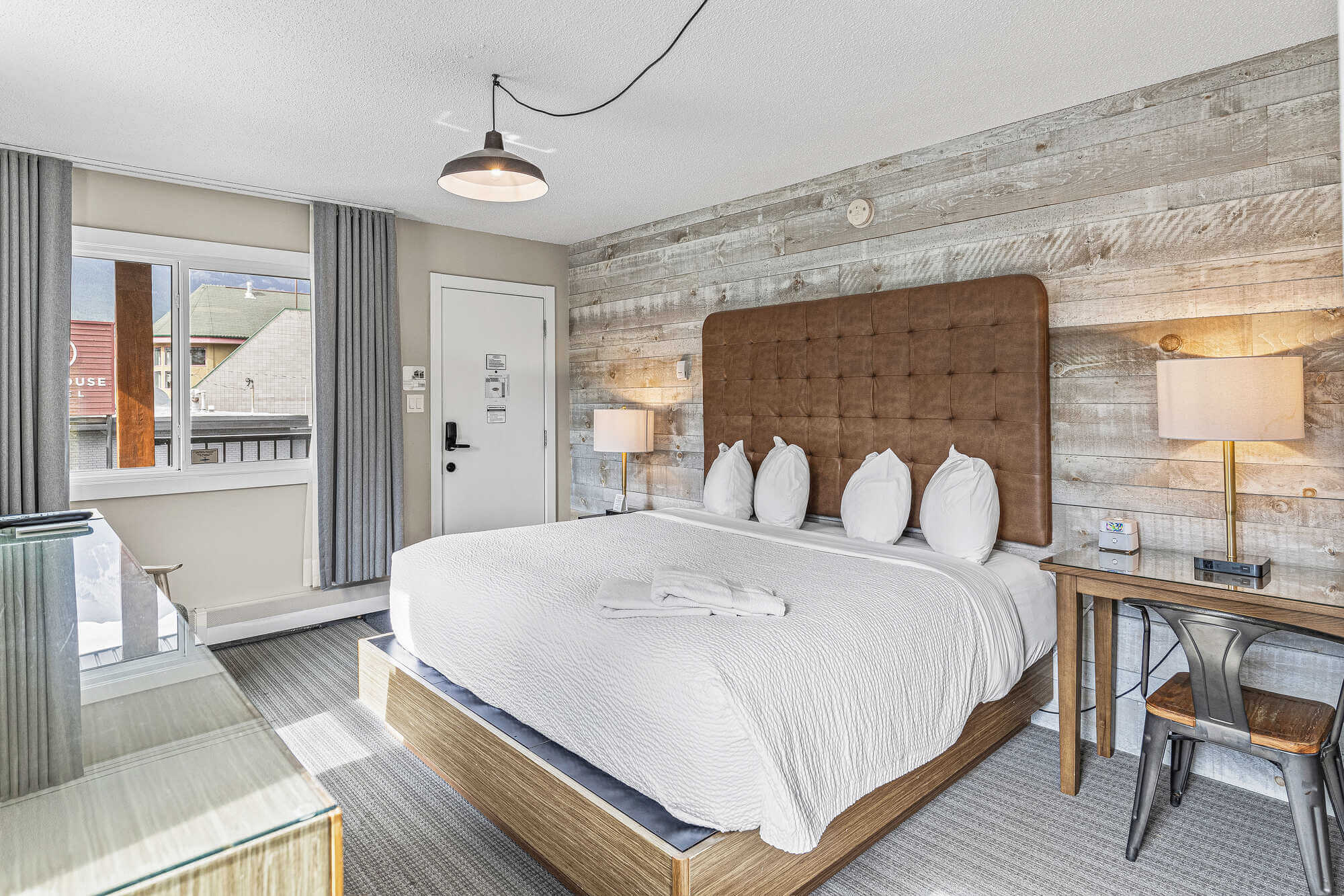 King bed in Basecamp Lamphouse Canmore hotel room with wood accent wall