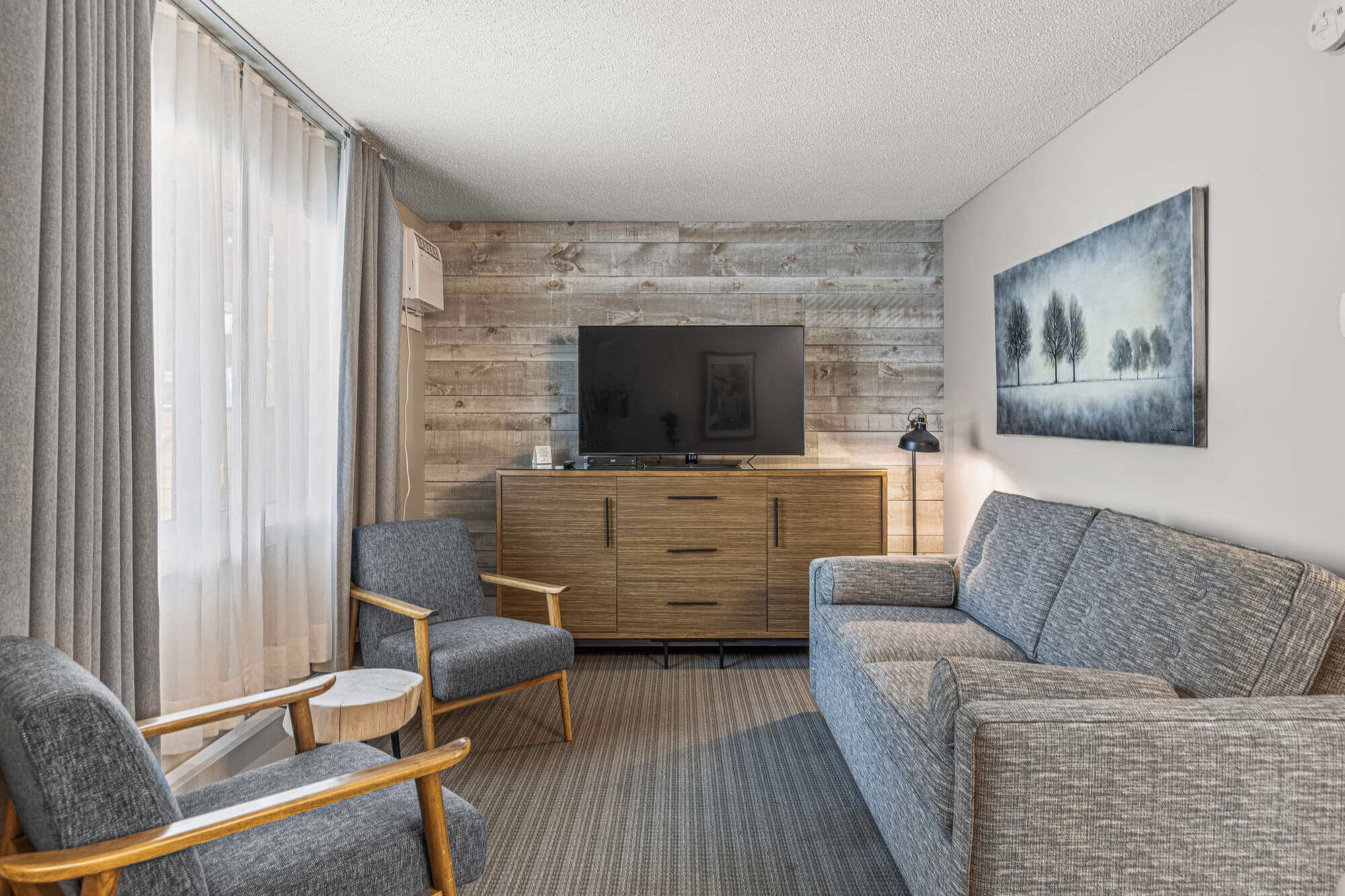 Basecamp Lamphouse Canmore Queen Suite: Living area with sofa, chairs, TV, and artwork.