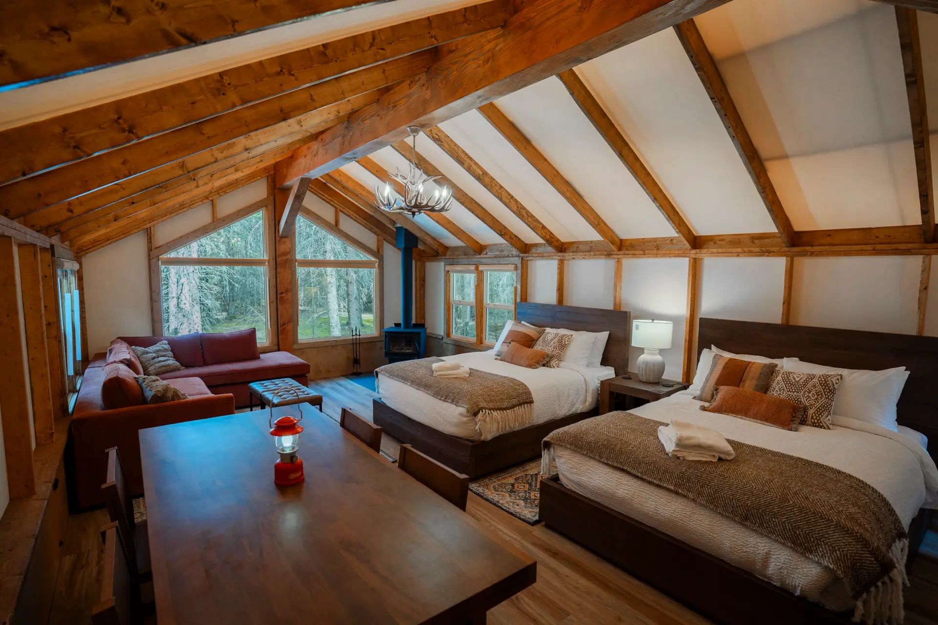 Basecamp Sundance family tent interior with two queen beds, sofa, and dining table.