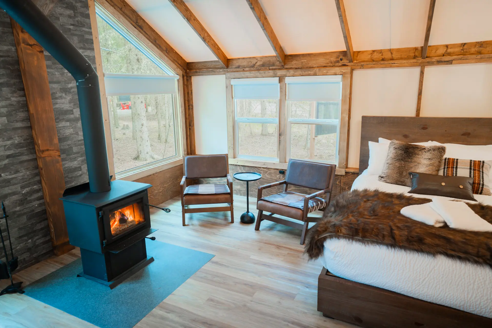 Cozy glamping tent interior with wood stove, chairs, and bed