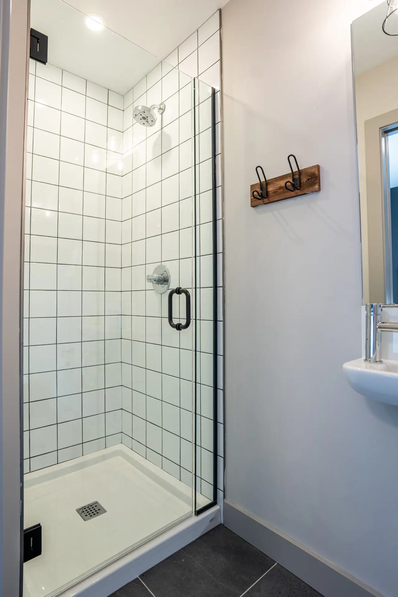 Modern shower stall with white tile and glass door in a hotel bathroom