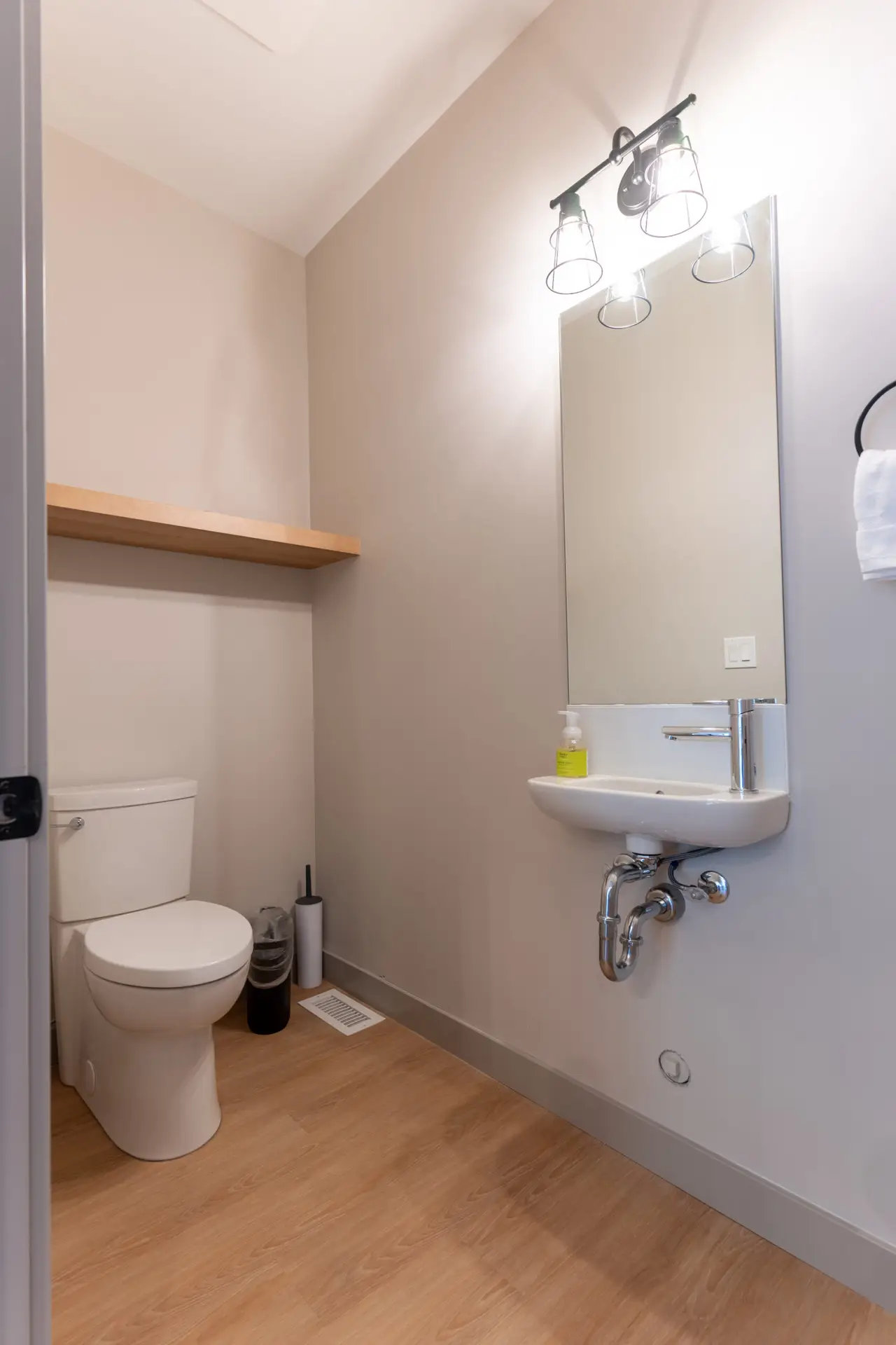 Modern bathroom with toilet, sink, and mirror in Basecamp Suites Revelstoke.
