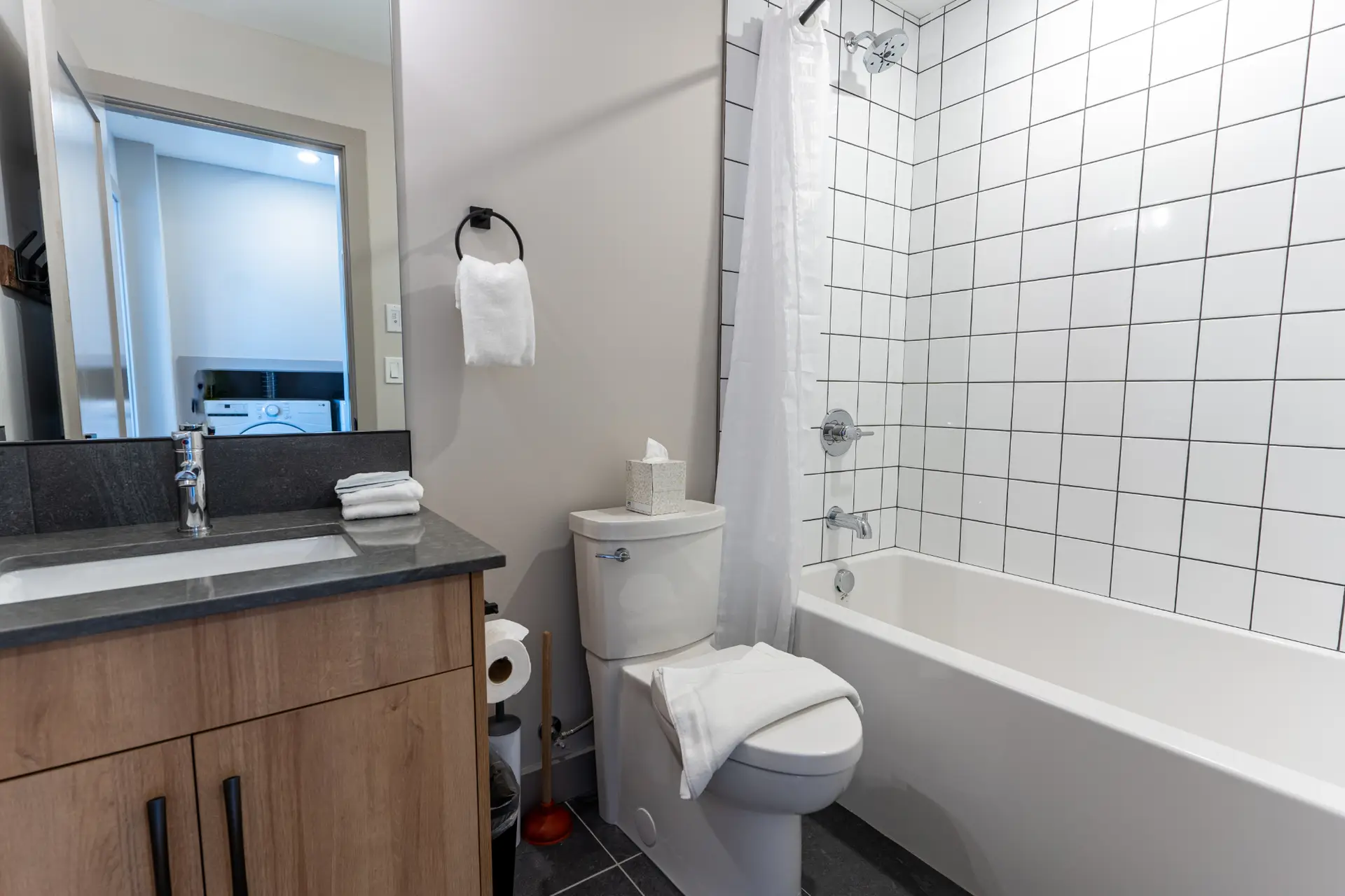 Modern bathroom with white subway tile shower, bathtub, and vanity in Basecamp Suites Revelstoke.