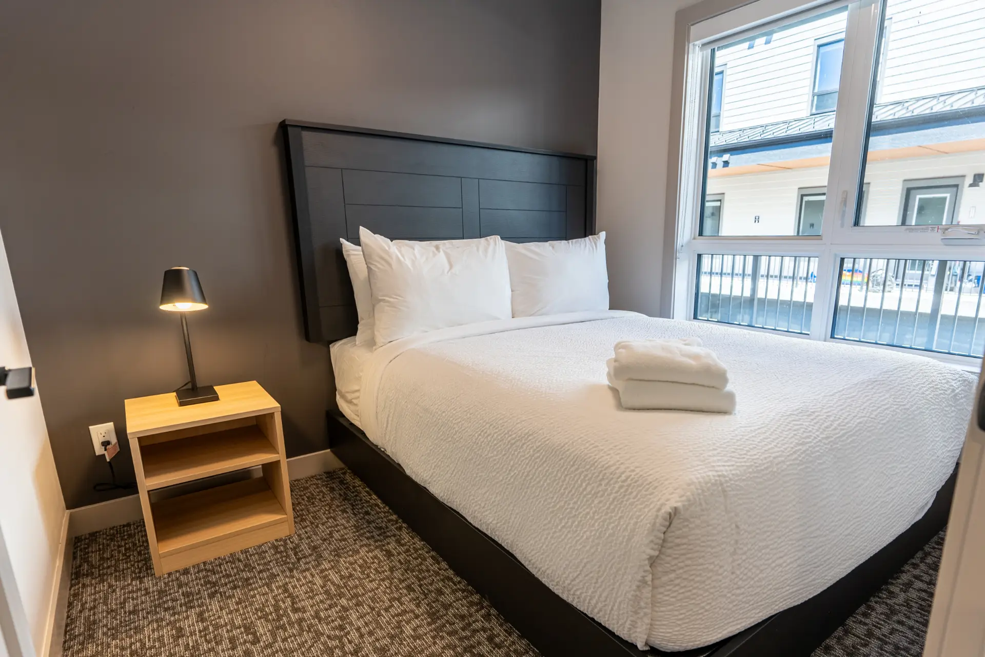 Basecamp Suites Revelstoke queen suite bedroom with large window and modern decor.