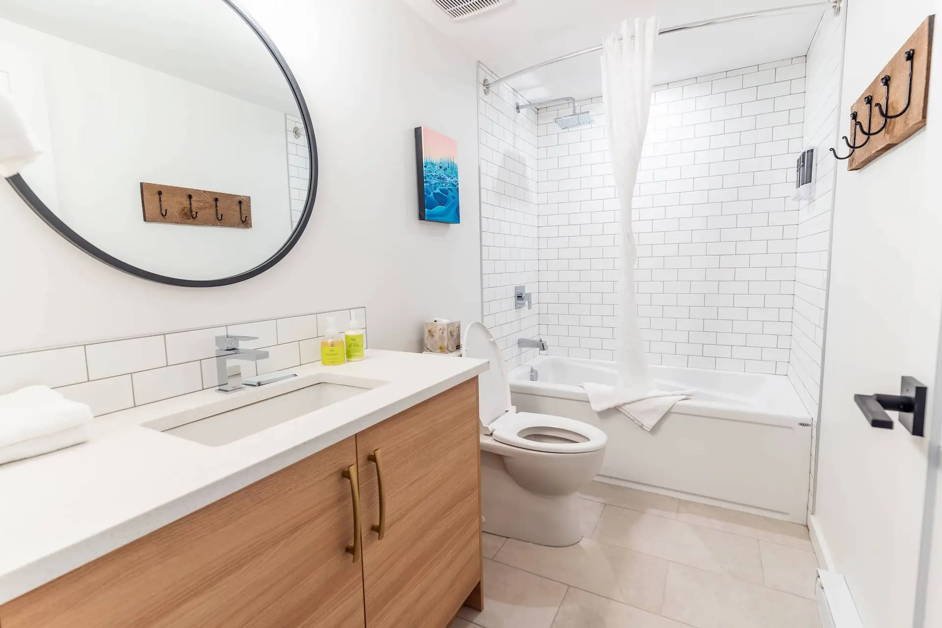 Modern bathroom with subway tile, wood vanity, and bathtub in a Basecamp Resort suite.