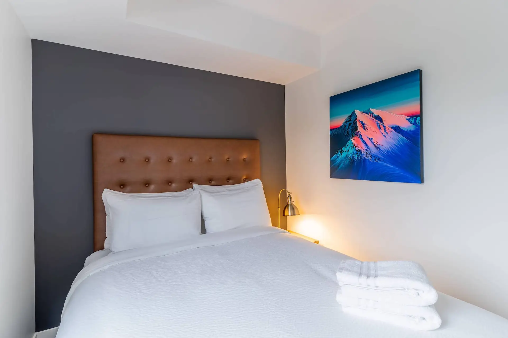 Revelstoke Five Bedroom Suite: King bed with brown tufted headboard and mountain art.