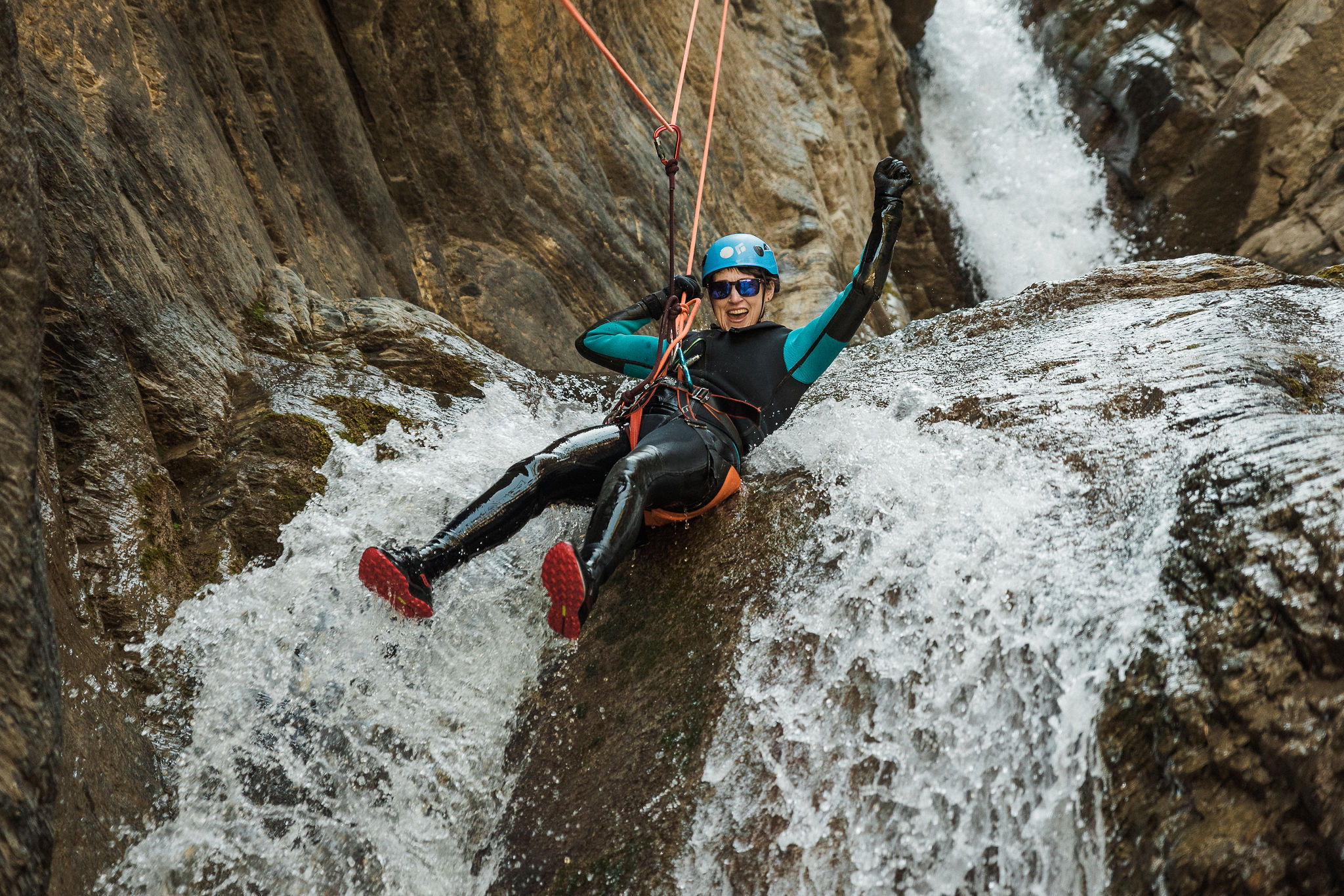 Excited person rappelling down a waterfall during Banff canyoning adventure.