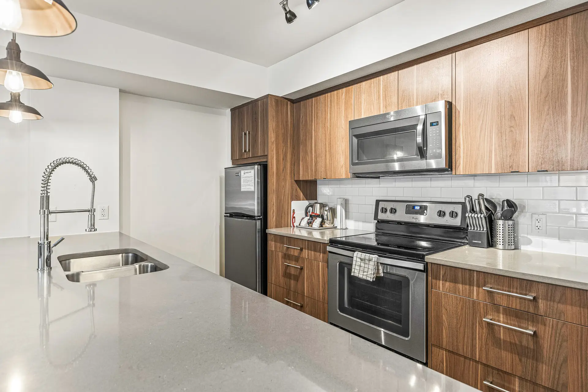 Modern kitchen with stainless steel appliances, wood cabinets, and quartz countertop.