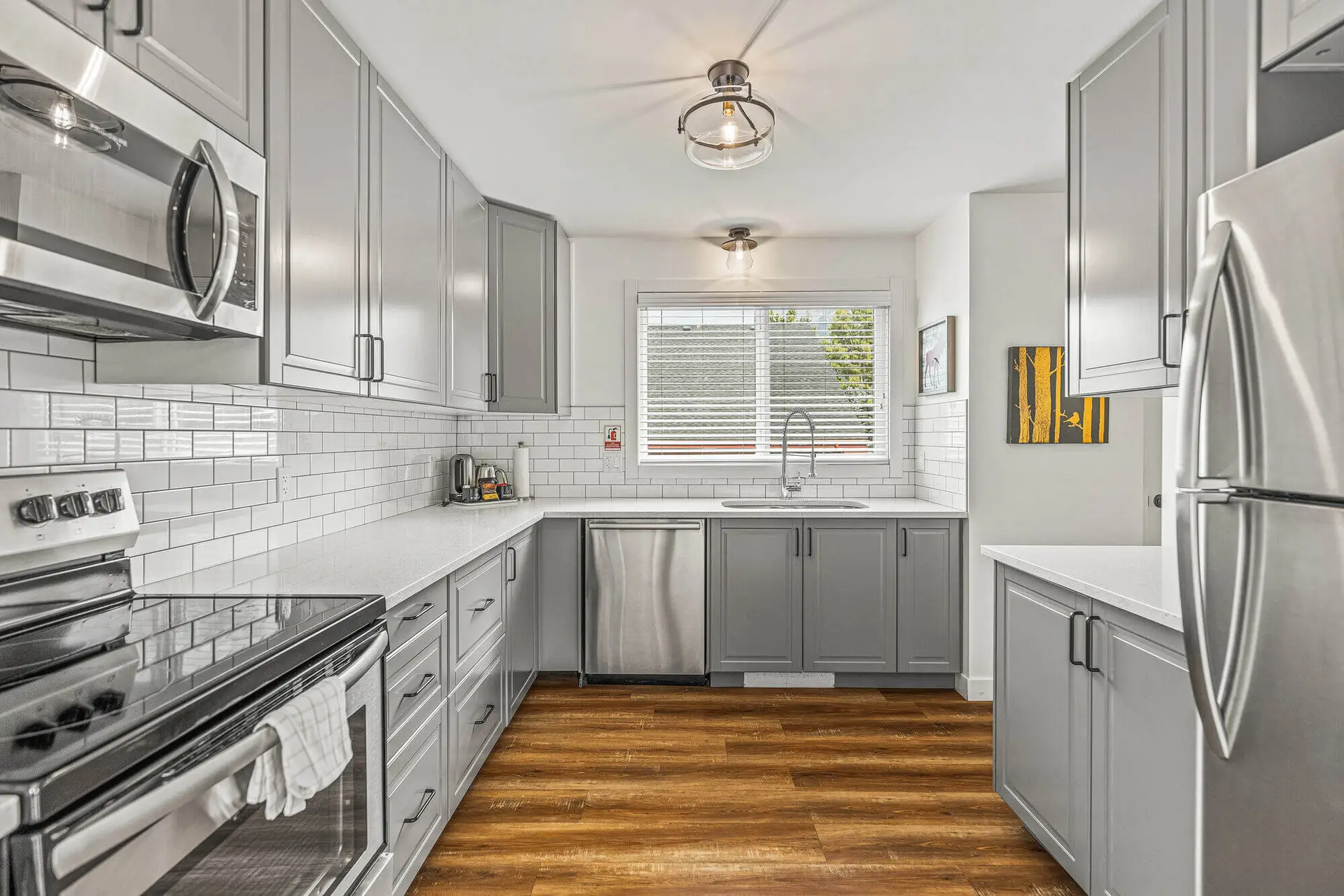 Modern grey kitchen with white subway tile backsplash and stainless steel appliances.