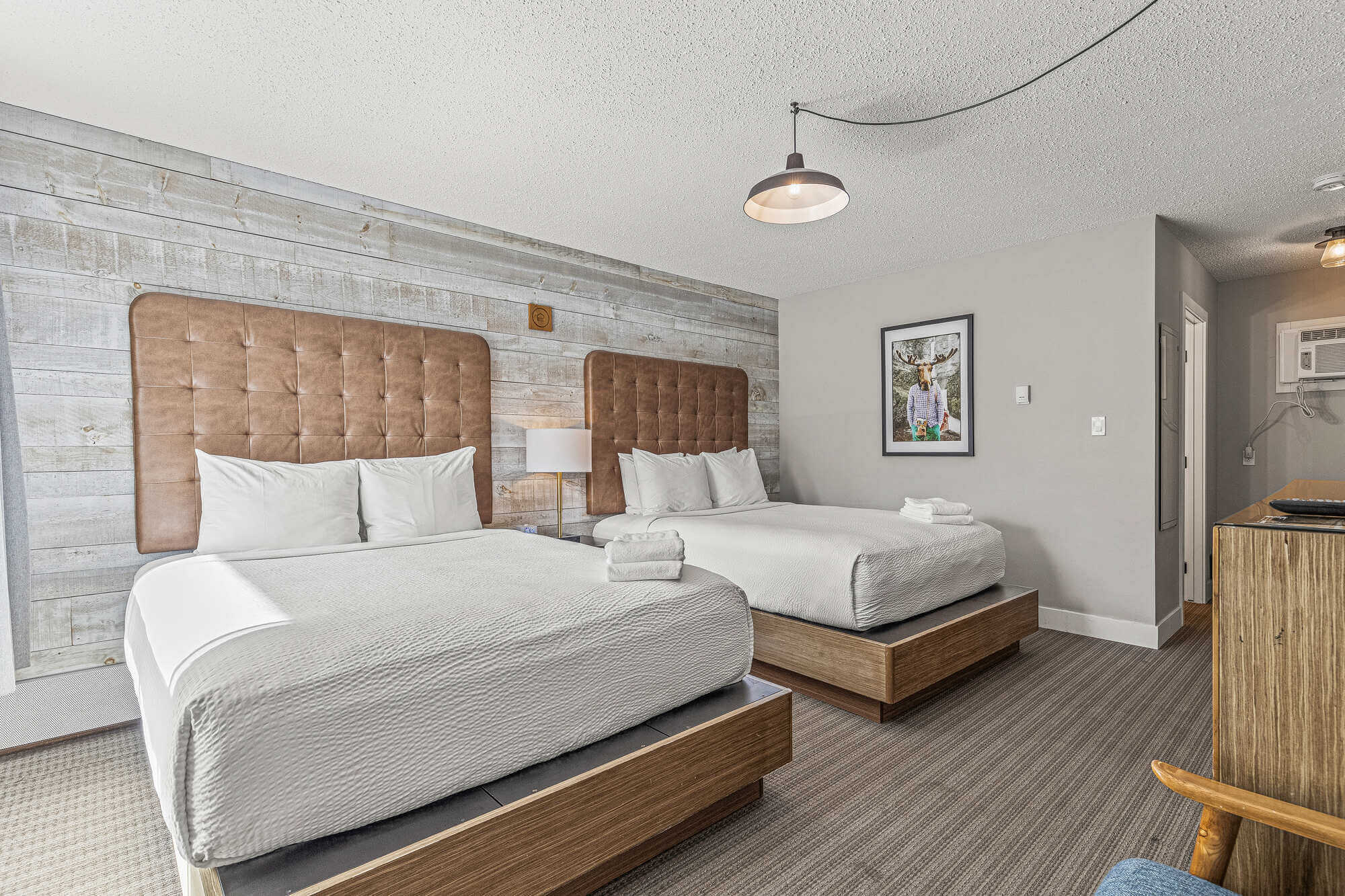 Basecamp Lamphouse Canmore double queen bedroom with rustic wood accent wall.