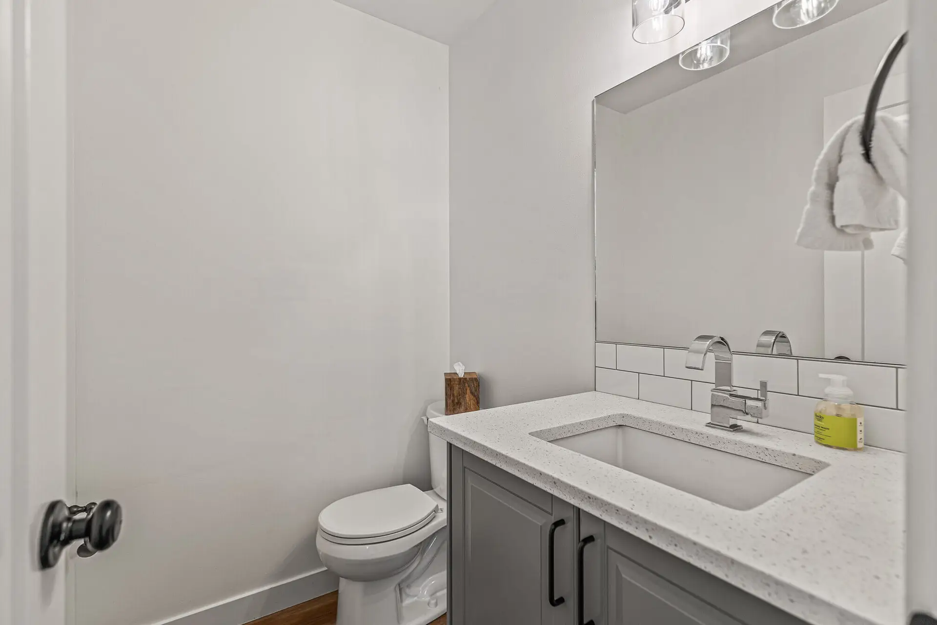 Modern powder room with white subway tile, gray vanity, and quartz countertop.